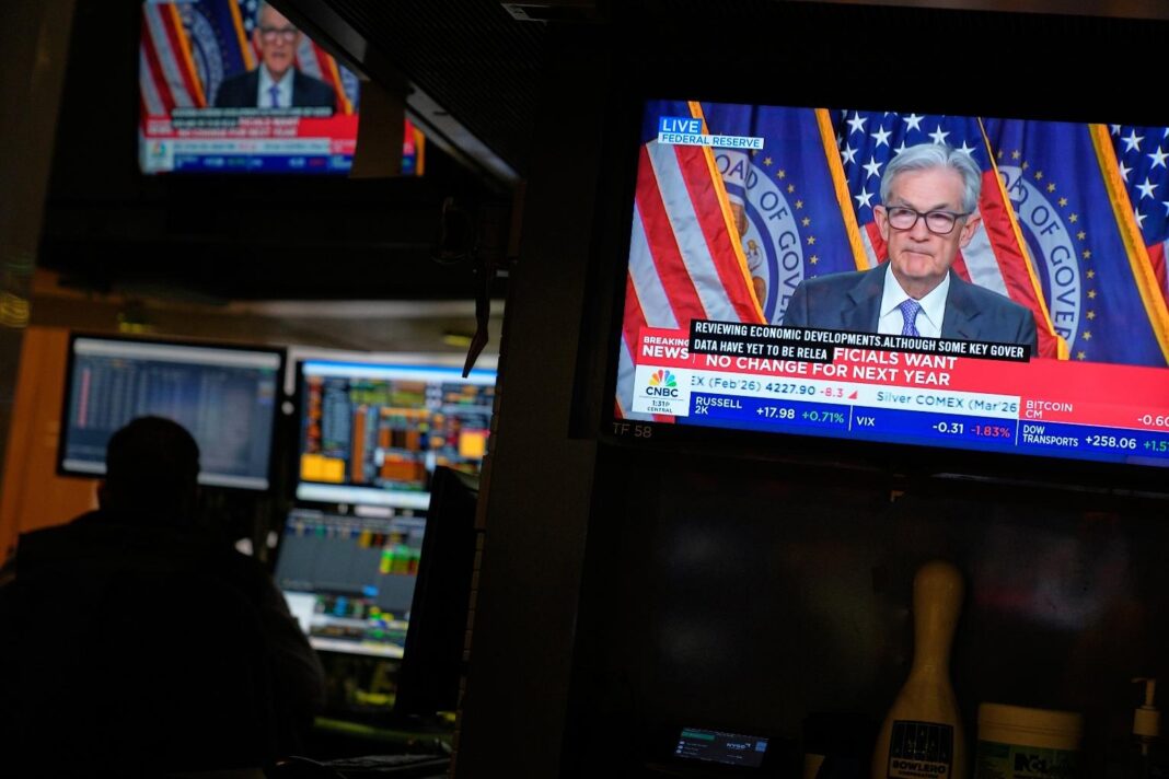 A television on the floor at the New York Stock Exchange in New York, display a news conference with Fed chairman Jerome Powell, Wednesday, Dec. 10, 2025. (AP Photo/Seth Wenig)